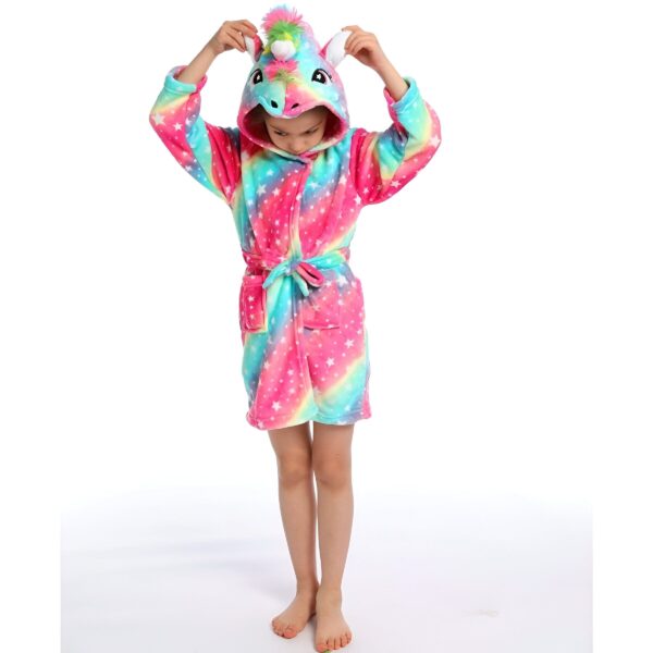 peignoir-licorne-ado-fille-3a.jpg Une jeune fille porte une robe de chambre licorne. La robe de chambre est rose et bleue avec des étoiles blanches. La capuche de la robe de chambre a la forme d'une tête de licorne avec une crinière arc-en-ciel.