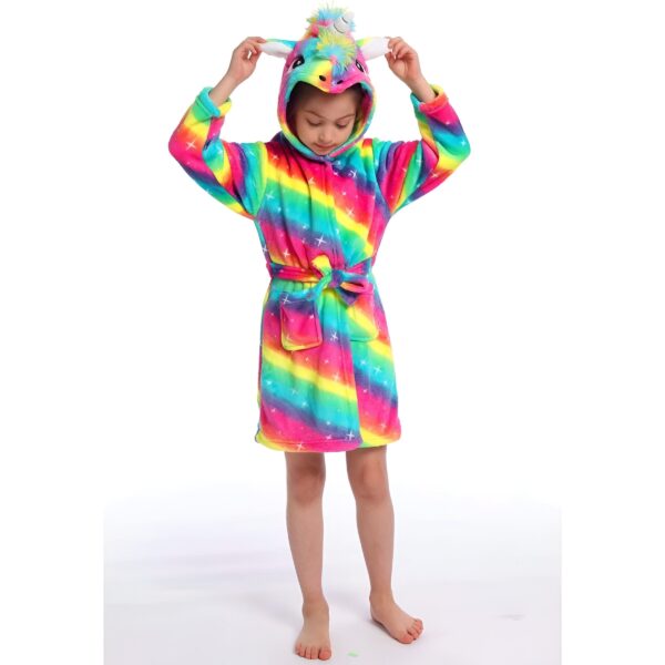 peignoir-licorne-arc-en-ciel-original-3a.jpg Une jeune fille porte une robe de chambre licorne arc-en-ciel avec une capuche. La robe de chambre est en peluche et a des étoiles blanches. La fille a les cheveux bruns et les yeux marron. Elle est pieds nus et se tient debout sur un fond blanc.