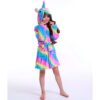 peignoir-licorne-enfant-arc-en-ciel-1a-1.jpg Une jeune fille porte une robe de chambre licorne arc-en-ciel à capuche. Elle a les cheveux longs et bruns et sourit à la caméra.