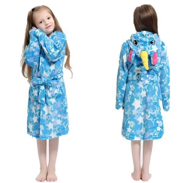 peignoir-licorne-enfant-bleu-ciel-en-coton-1a.jpg Une jeune fille porte une robe de chambre bleue à capuche en forme de licorne. La robe de chambre est ornée d'étoiles roses et jaunes. La capuche est dotée d'une corne de licorne et d'oreilles roses. La robe de chambre est ceinturée à la taille.