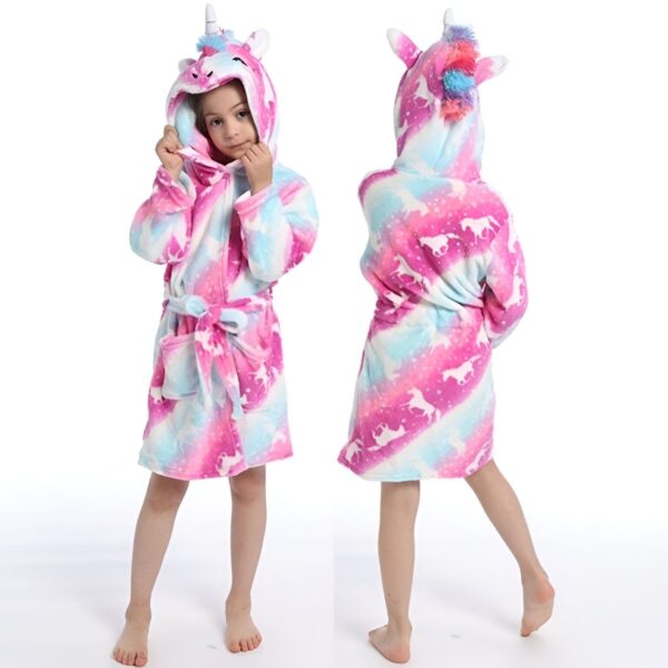 Une jeune fille porte une robe de chambre rose et violette à capuche en forme de licorne. La robe de chambre est ornée de motifs de licornes et de nuages.