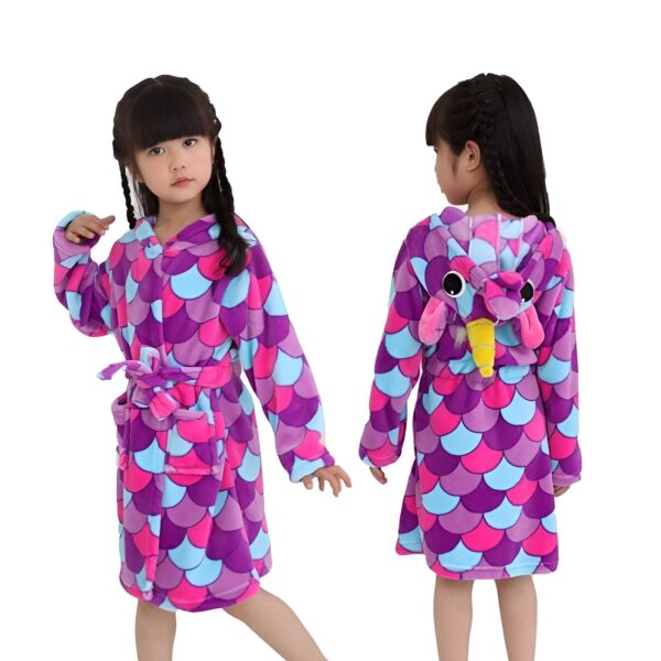 peignoir-licorne-enfant-violet-a-capuche-1a-1.jpg Une jeune fille porte une robe de chambre licorne violette et rose. La robe de chambre a une capuche avec une tête de licorne en 3D. La robe de chambre est également dotée d'une ceinture.