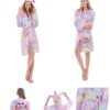 peignoir-licorne-femme-etoile-2a.jpg Une jeune femme porte un peignoir licorne rose et violet avec une capuche et des étoiles. Elle est souriante et joyeuse.