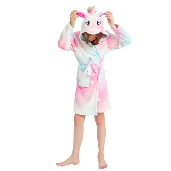 peignoir-licorne-fille-couleur-pale-1a.jpg Une jeune fille porte une combinaison pyjama licorne rose et bleue à capuche avec des étoiles blanches.