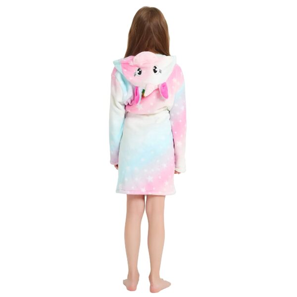 peignoir-licorne-fille-couleur-pale-5a.jpg Une jeune fille porte une robe de chambre licorne rose et bleue avec une capuche. La robe de chambre est en peluche et a des étoiles et des lunes imprimées. La capuche est en forme de tête de licorne avec une corne et des oreilles. La jeune fille est vue de dos.