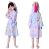 peignoir-licorne-fille-etoile-4a.jpg Une petite fille porte une robe de chambre licorne violette avec des étoiles et une capuche. La robe de chambre est attachée avec une ceinture. La petite fille a les cheveux bruns et elle sourit.