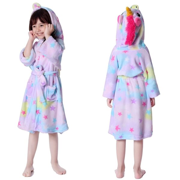 peignoir-licorne-fille-etoile-4a.jpg Une petite fille porte une robe de chambre licorne violette avec des étoiles et une capuche. La robe de chambre est attachée avec une ceinture. La petite fille a les cheveux bruns et elle sourit.