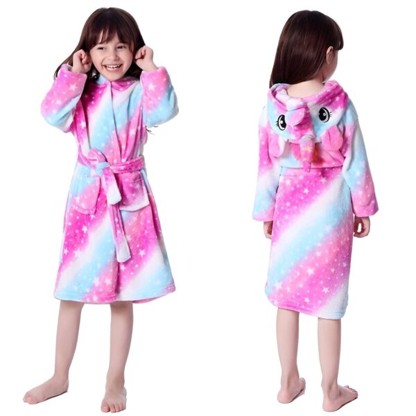 peignoir-licorne-fille-galaxie-1a-1.jpg Une jeune fille porte une combinaison pyjama licorne rose et blanche à capuche avec des étoiles filantes.