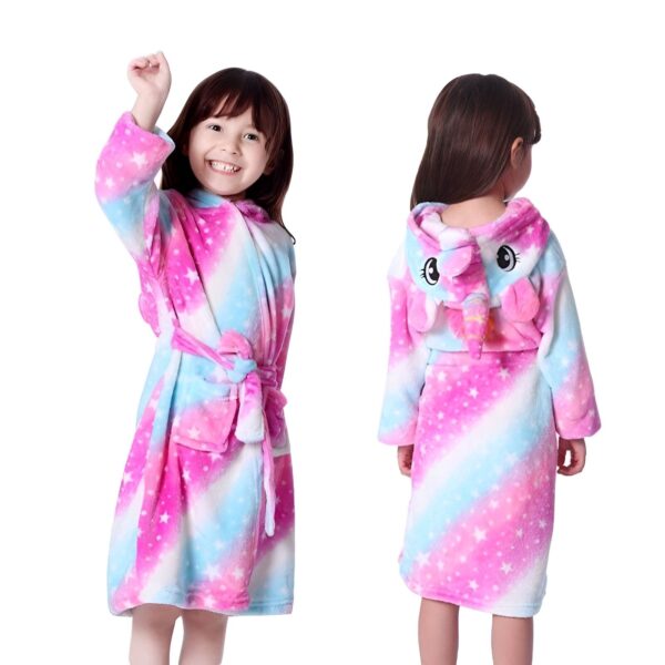 peignoir-licorne-fille-galaxie-3a.jpg Une petite fille porte une robe de chambre licorne rose et bleue à capuche. La robe de chambre est ouverte, on peut voir qu'elle porte un pyjama licorne rose et blanc. Elle a les cheveux bruns et les yeux marron. Elle est souriante et joyeuse.