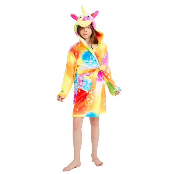 peignoir-licorne-fille-jaune-en-coton-1a.jpg Une jeune fille porte une robe de chambre licorne arc-en-ciel avec une capuche. La robe de chambre est en peluche et a des étoiles multicolores. La capuche a une corne de licorne et des oreilles de licorne. La jeune fille est pieds nus et a les cheveux longs et blonds.