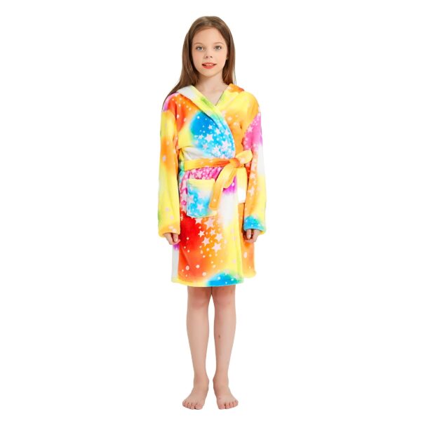 Une jeune fille porte une robe de chambre à capuche arc-en-ciel avec des étoiles blanches. La robe de chambre est attachée avec une ceinture. La fille a les cheveux bruns et les yeux bleus. Elle est pieds nus et se tient debout sur un fond blanc.