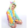Une jeune fille porte une combinaison pyjama licorne arc-en-ciel avec une capuche.