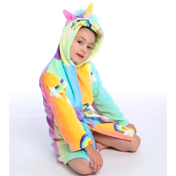 Une jeune fille porte une combinaison pyjama licorne arc-en-ciel avec une capuche.