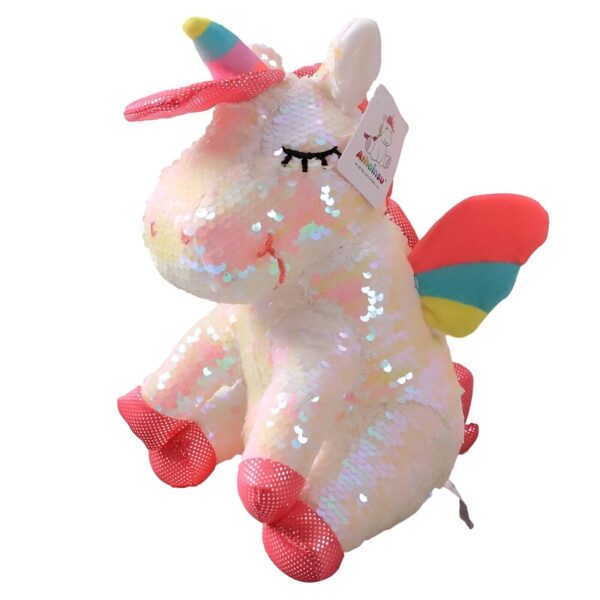Une peluche licorne blanche avec des ailes arc-en-ciel et une crinière et une queue roses. La peluche est recouverte de paillettes réversibles qui peuvent être retournées pour changer de couleur.