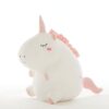 peluche-licorne-ronde-blanche-25cm-1a.jpg Une peluche licorne blanche et rose avec une crinière et une queue roses. La peluche est assise et a les yeux fermés.