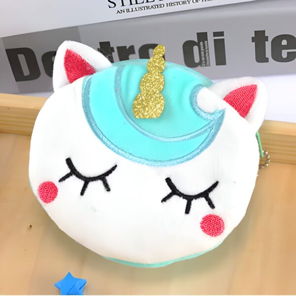 peluche-sac-a-main-licorne-transformable-1a.jpg Image d'un porte-monnaie en forme de tête de licorne blanche avec une corne dorée scintillante, des joues roses et des yeux brodés fermés. Le contour de la tête est turquoise., 45501164847359 | Licorne Shop