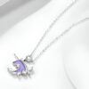 Un collier avec un pendentif en forme de licorne. La licorne est violette avec une crinière et une queue roses. Le pendentif est entouré de feuilles et de fleurs. La chaîne est en argent.