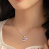 Une jeune femme porte un collier avec un pendentif en forme de licorne. La licorne est violette et a une crinière et une queue roses. Le pendentif est en argent et est serti de zircons cubiques. La chaîne est en argent et est réglable.