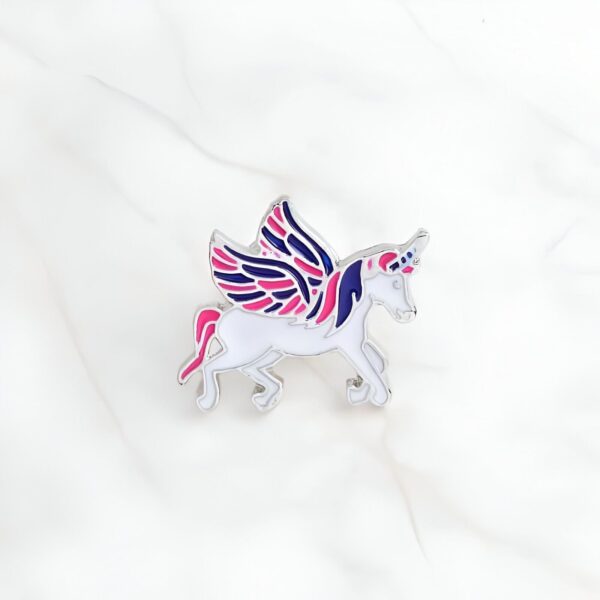 pin-s-licorne-fantaisie-1a.jpg Broche émaillée représentant une licorne blanche avec des ailes bicolores (rose et bleu marine). Détails argentés. Style enfantin et fantaisie. Accessoire de mode original., 45501794550015 | Licorne Shop