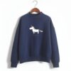 pull-licorne-femme-bleu-fonce-1a.jpg Une image d'un sweat-shirt bleu marine avec une illustration d'une licorne blanche et dorée. La licorne a une crinière et une queue dorées, et porte un collier avec un pendentif en forme de cœur. Le sweat-shirt a un col montant et des manches longues.