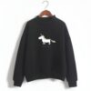 pull-licorne-femme-noir-1a.jpg Une image d'un sweat-shirt noir avec une illustration d'une licorne dorée. La licorne est représentée de profil, avec une crinière et une queue dorées. Le sweat-shirt a un col montant et des manches longues.
