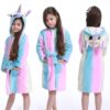 Une petite fille portant un peignoir de bain doux à capuche en forme de licorne, rayé de couleurs pastel rose, bleu et blanc. Vues de face et de dos., 45502350983423,45502351016191,45502351048959,45502351081727,45502351114495,45502351147263,45502351180031,45502351212799 | Licorne Shop