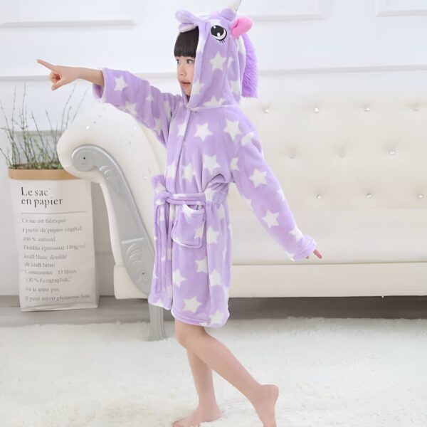 robe-licorne-a-capuche-pour-enfant-1a.jpg Enfant portant un peignoir en forme de licorne violet avec des étoiles blanches, souriant et pointant du doigt, posant devant un canapé blanc., 45502026580223,45502026612991,45502026645759,45502026678527,45502026711295,45502026744063,45502026776831,45502026809599 | Licorne Shop