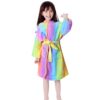 Une jeune fille souriante porte un peignoir arc-en-ciel doux avec une ceinture. Le peignoir semble chaud et confortable, parfait pour se détendre après le bain., 45502022418687,45502022451455,45502022484223,45502022516991,45502022549759,45502022582527,45502022615295,45502022648063 | Licorne Shop
