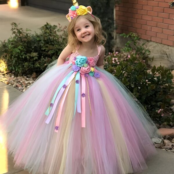 robe-licorne-fille-arc-en-ciel-6-mois-a-9-ans-1a.jpg Une petite fille porte une robe de princesse en tulle arc-en-ciel avec une licorne sur la tête.
