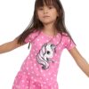 Une petite fille porte une robe rose à pois blancs avec une image de licorne. La licorne est blanche avec une crinière et une queue roses.
