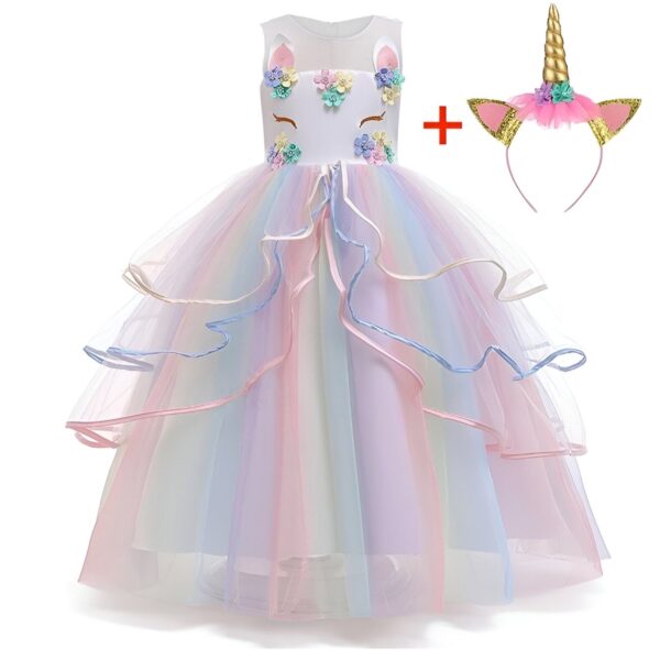 Une robe de licorne blanche et rose avec des fleurs et des paillettes. La robe est composée de plusieurs couches de tulle et est très volumineuse. Elle est accompagnée d'un serre-tête avec une corne de licorne.