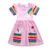 Une robe rose à manches courtes pour fille avec une poche arc-en-ciel sur le devant. La robe est également dotée d'un motif de licorne et de papillons.