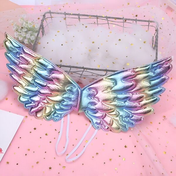 robe-princesse-licorne-fille-bleu-2a.jpg Une paire d'ailes d'ange arc-en-ciel avec des détails scintillants. Les ailes sont faites d'un matériau léger et iridescent qui reflète la lumière. Elles sont attachées par des rubans blancs qui se nouent autour du cou et du dos. Les ailes sont parfaites pour un costume de fée, de princesse ou de papillon.
