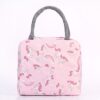 Sac à déjeuner isotherme rose avec des motifs d'licornes, arc-en-ciels et nuages blancs. Le sac possède une poignée de transport grise sur le dessus et une poche frontale., 45501373415679 | Licorne Shop