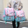 Une image de deux enfants portant des sacs à dos. Les sacs à dos sont bleus et roses et ont une image de licorne dessus.