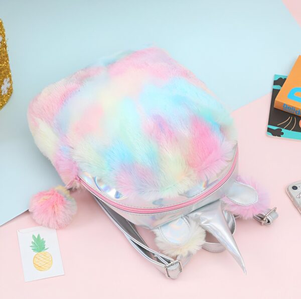 Un sac à dos en forme de licorne en peluche arc-en-ciel avec une corne et des oreilles en argent.