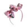 serre-tete-licorne-rose-a-corne-doree-et-paillettes-1a.jpg Serre-tête rose pour enfant avec un grand nœud JoJo Siwa. Le nœud est rose et décoré de motifs licornes, arcs-en-ciel, étoiles et cœurs. L'emballage est visible en haut à droite., 45501376168191 | Licorne Shop