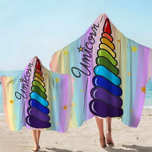 serviette-de-plage-licorne-en-microfibre-avec-capuche-2a.jpg Deux personnes sur la plage, enveloppées dans des serviettes à capuche à motif d'une licorne arc-en-ciel., 45501225828607 | Licorne Shop