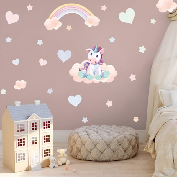 sticker-licorne-petite-fille-2a.jpg Une chambre d'enfant avec une décoration de licorne. Il y a un lit, une maison de poupée, un pouf et des nuages, des étoiles et des cœurs en guise de décoration murale.