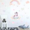 sticker-licorne-petite-fille-4a.jpg Une illustration d'une licorne assise sur un nuage avec un arc-en-ciel et des étoiles en arrière-plan.