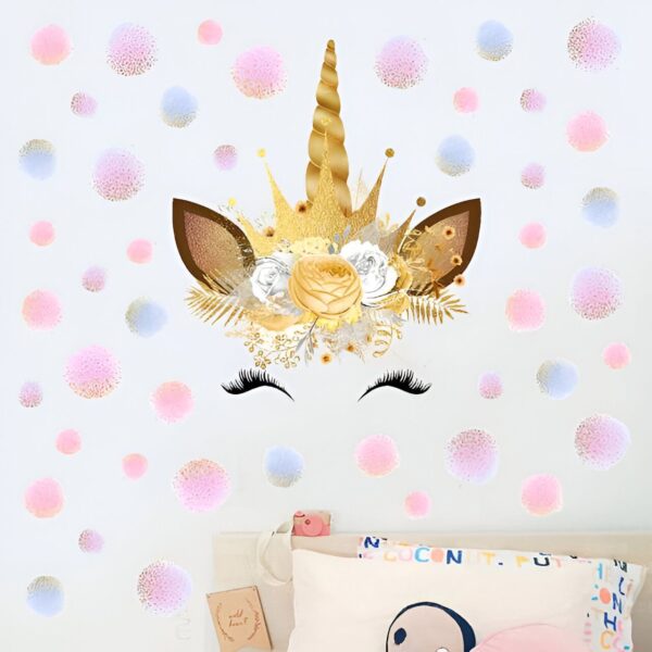 sticker-licorne-princesse-1a.jpg Une illustration d'une tête de licorne avec une couronne de fleurs. La licorne est dorée avec des fleurs roses et blanches. Il y a des points roses et bleus autour de la licorne.