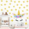 Une chambre d'enfant avec une décoration de licorne. La licorne a une crinière et une queue roses, et des fleurs sur la tête. Il y a des étoiles dorées qui brillent dans le fond.
