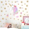 Une licorne blanche avec une crinière arc-en-ciel et des étoiles dorées autour d'elle. Il y a aussi un cupcake et un nœud rose.
