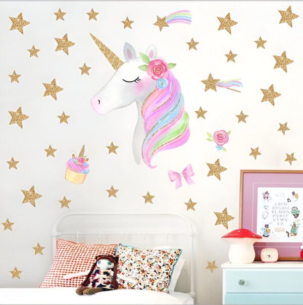 Une licorne blanche avec une crinière arc-en-ciel et des étoiles dorées autour d'elle. Il y a aussi un cupcake et un nœud rose.