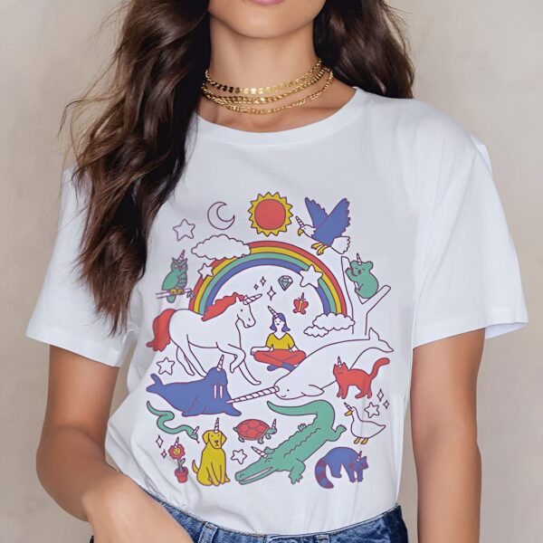 t-shirt-a-imprime-licorne-pastel-la-petite-cible-1a.jpg Femme portant un t-shirt blanc avec un dessin coloré d'animaux avec des cornes de licorne, un arc-en-ciel, le soleil, la lune, et des étoiles., 45502304583935,45502304616703,45502304649471,45502304682239,45502304715007,45502304747775,45502304780543,45502304813311 | Licorne Shop