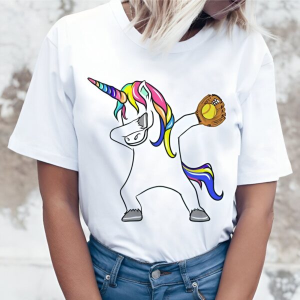 t-shirt-licorne-dab-baseball-1a.jpg Une illustration d'une licorne qui fait un dab avec une balle de softball dans un gant de baseball. La licorne est blanche avec une crinière et une queue arc-en-ciel. Elle porte un maillot de baseball blanc et un pantalon bleu. Le gant de baseball est marron et la balle de softball est jaune avec des coutures rouges.
