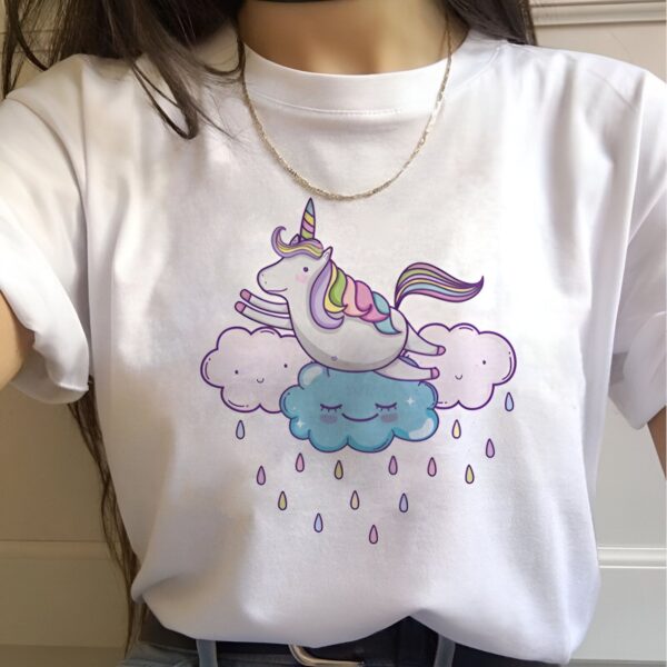 t-shirt-licorne-dans-les-nuages-1a.jpg Une illustration d'une licorne blanche avec une crinière et une queue arc-en-ciel sautant sur un nuage. La licorne est entourée de nuages et de pluie.