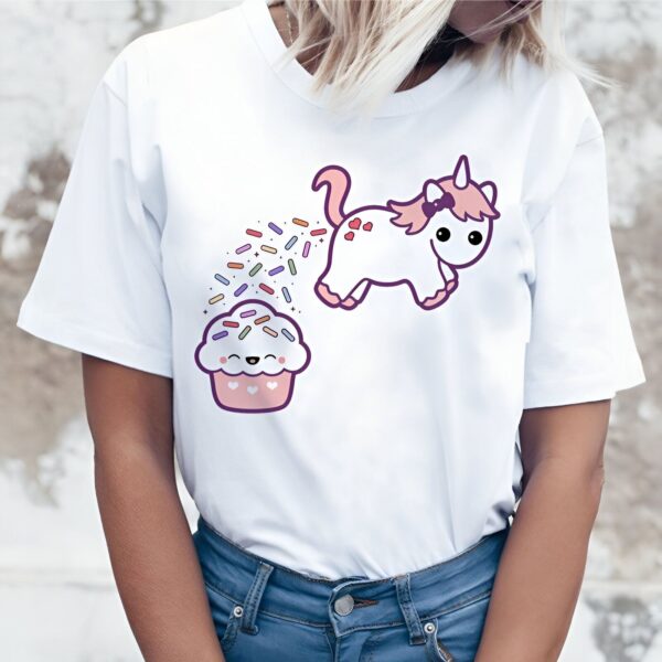 t-shirt-licorne-gateau-1a.jpg Une illustration d'une licorne rose qui défèque sur un cupcake. La licorne est debout sur le côté droit de l'image et le cupcake est sur le côté gauche. La licorne a une crinière et une queue arc-en-ciel. Le cupcake a un visage souriant et des pépites de couleur.