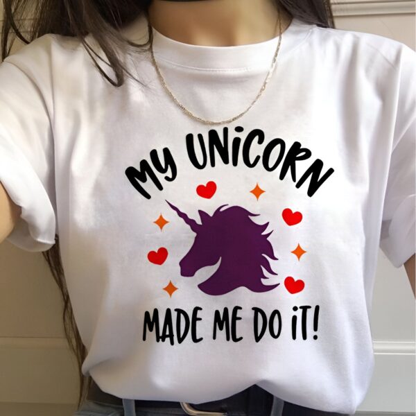 Une femme porte un t-shirt blanc avec écrit "My unicorn made me do it" (Ma licorne m'a fait le faire) avec une illustration d'une licorne violette.