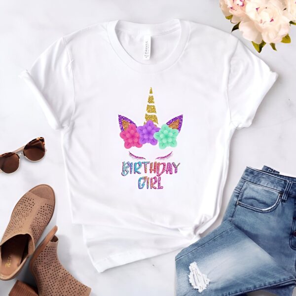 t-shirt-motif-licorne-1a.jpg T-shirt blanc avec motif de licorne florale et l'inscription "Birthday Girl". Des lunettes de soleil, des chaussures et un jean sont également visibles. Idée de cadeau d'anniversaire pour fille., 45502331846911,45502331879679,45502331912447,45502331945215,45502331977983,45502332010751,45502332043519,45502332076287 | Licorne Shop